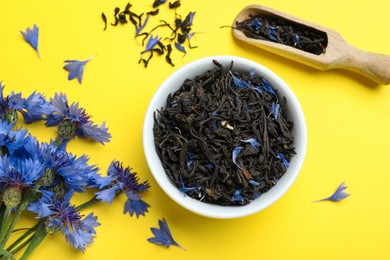 Photo of Flat lay composition with dry tea leaves and cornflowers on yellow background