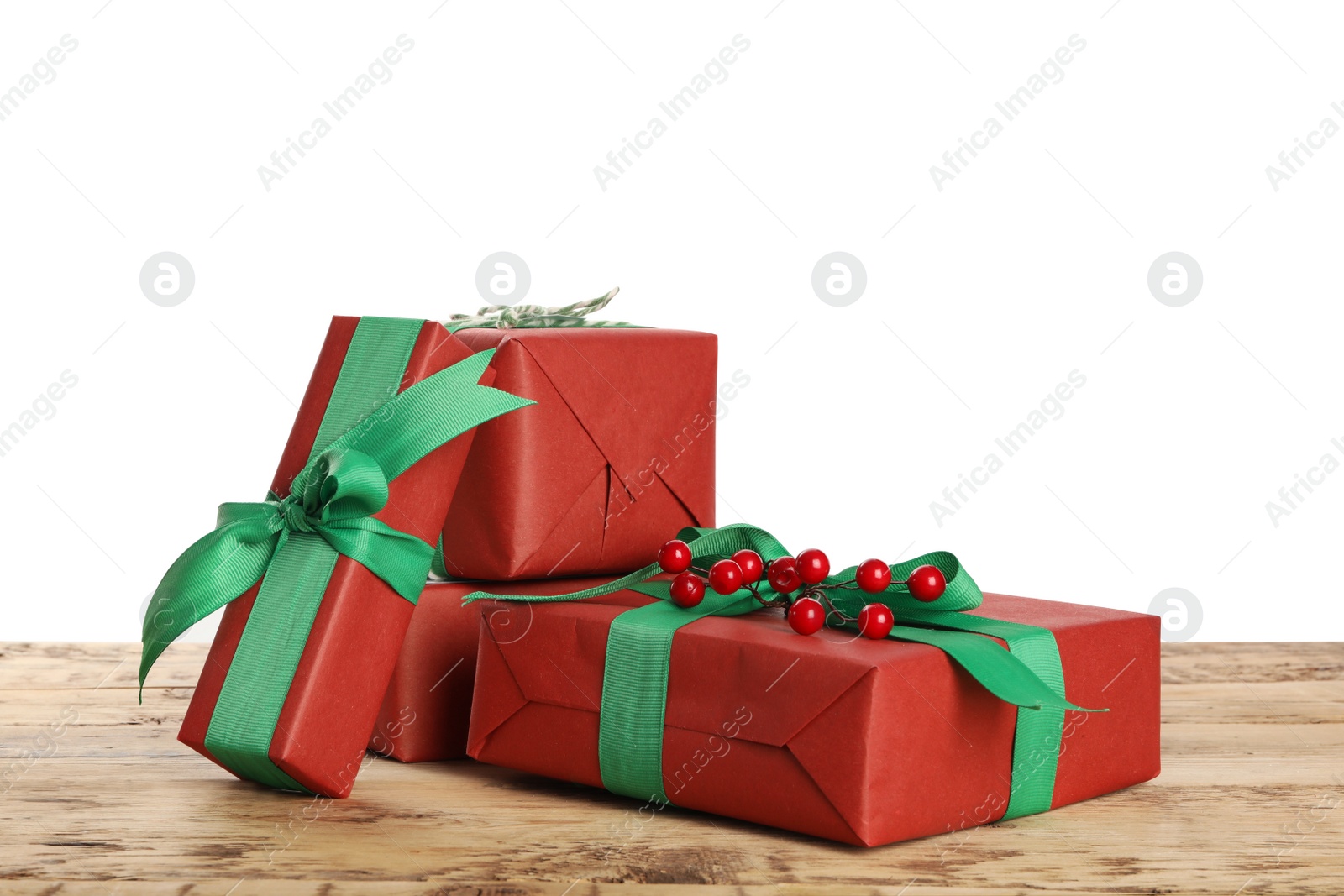 Photo of Christmas gifts with red berries on wooden table against white background