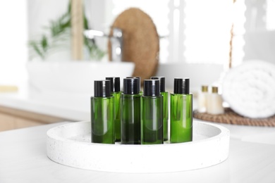 Photo of Mini bottles with cosmetic products on white table in bathroom