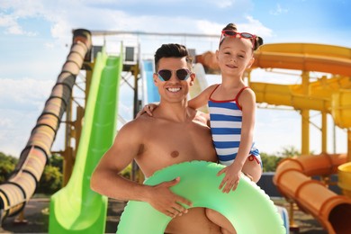Photo of Father and daughter with inflatable ring in water park. Family vacation