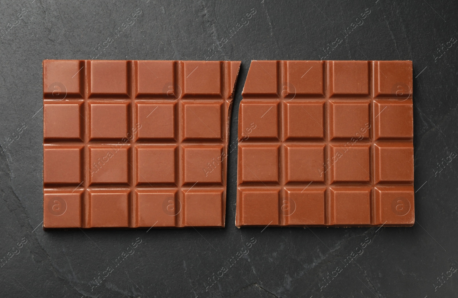 Photo of Tasty broken chocolate bar on grey table, top view