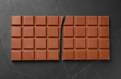 Photo of Tasty broken chocolate bar on grey table, top view