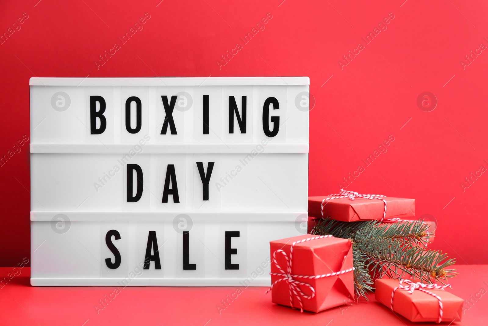 Photo of Lightbox with phrase BOXING DAY SALE and Christmas decorations on red background