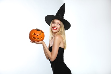 Beautiful woman in witch costume with jack o'lantern on white background. Halloween party