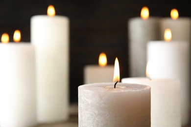 Photo of Alight wax candle on blurred background, closeup. Space for text