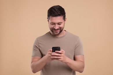 Photo of Happy man using smartphone on beige background