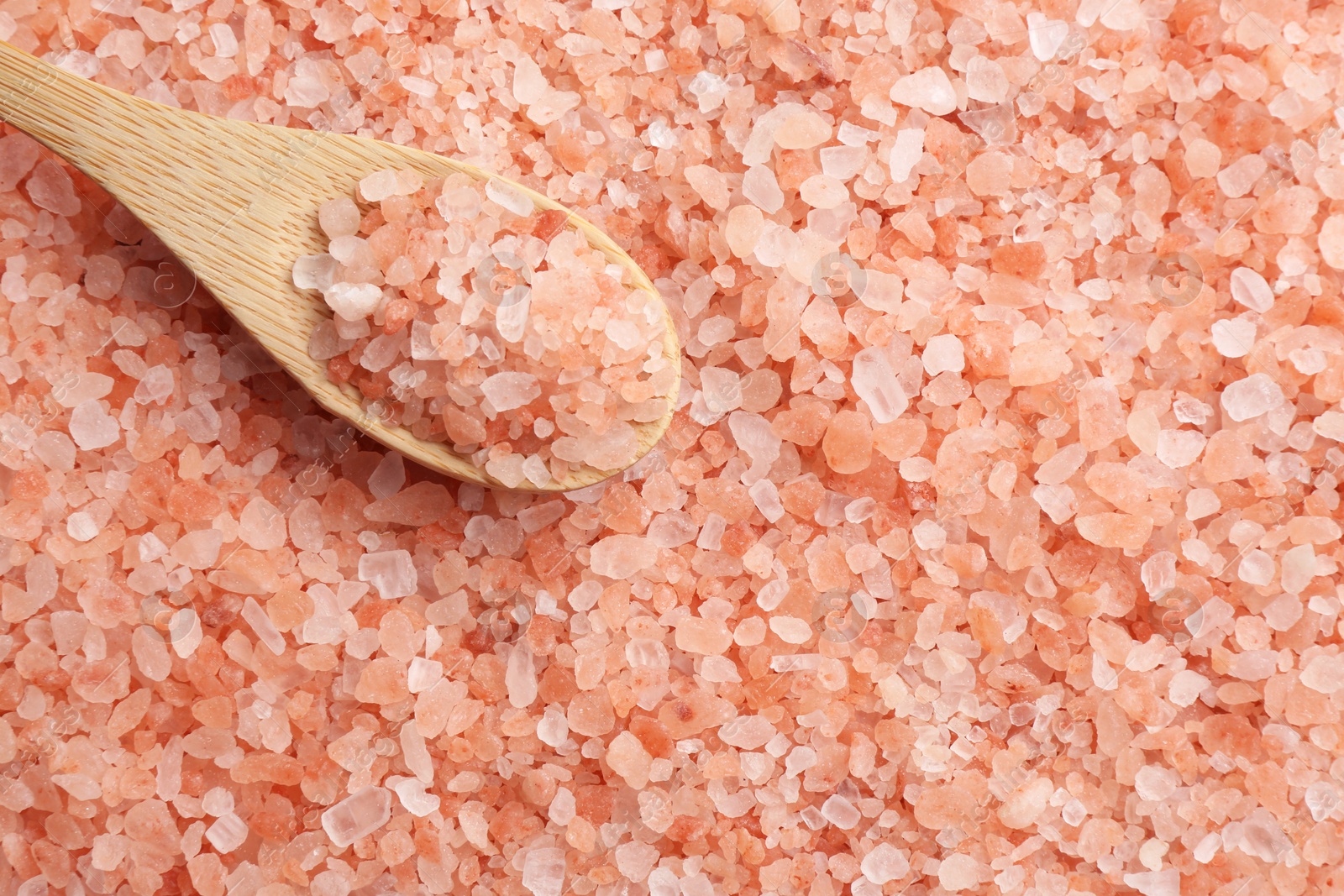 Photo of Pink himalayan salt and wooden spoon as background, top view