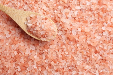 Pink himalayan salt and wooden spoon as background, top view