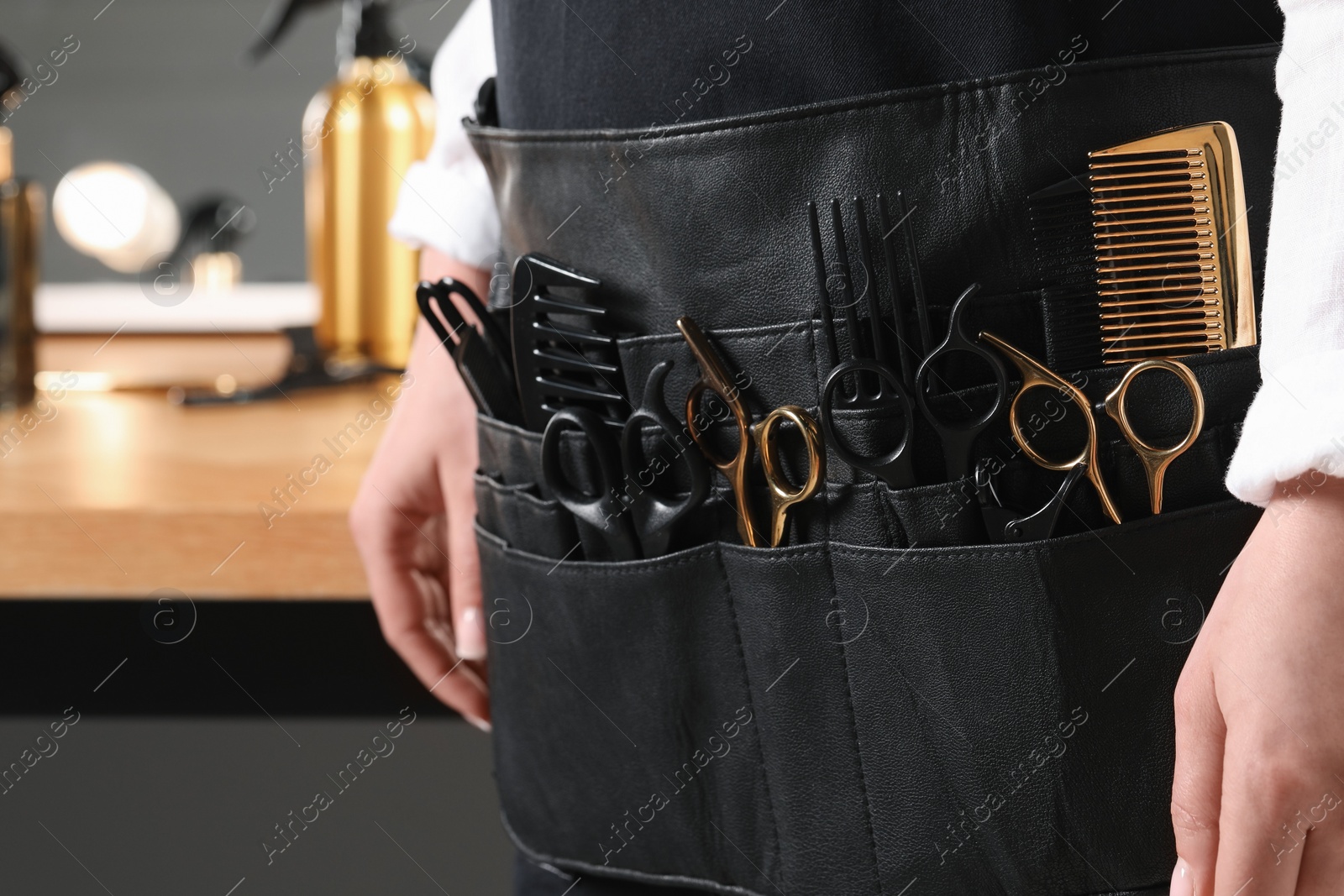 Photo of Hairstylist with professional tools in waist pouch in salon, closeup