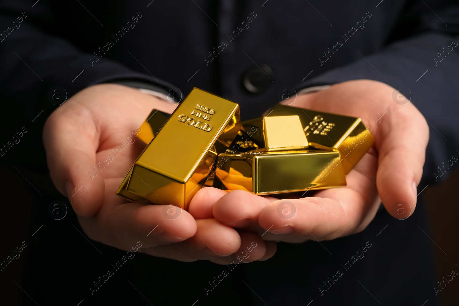 Photo of Man holding many shiny gold bars, closeup