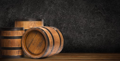 Wooden barrels against dark textured background, space for text. Banner design