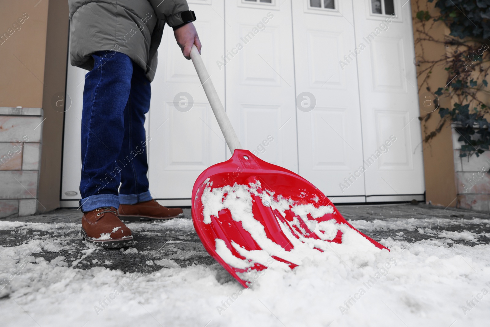 Photo of Man removing snow with shovel near building outdoors, closeup