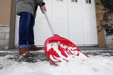 Photo of Man removing snow with shovel near building outdoors, closeup
