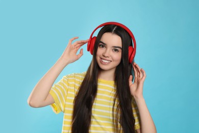 Teenage girl listening music with headphones on light blue background