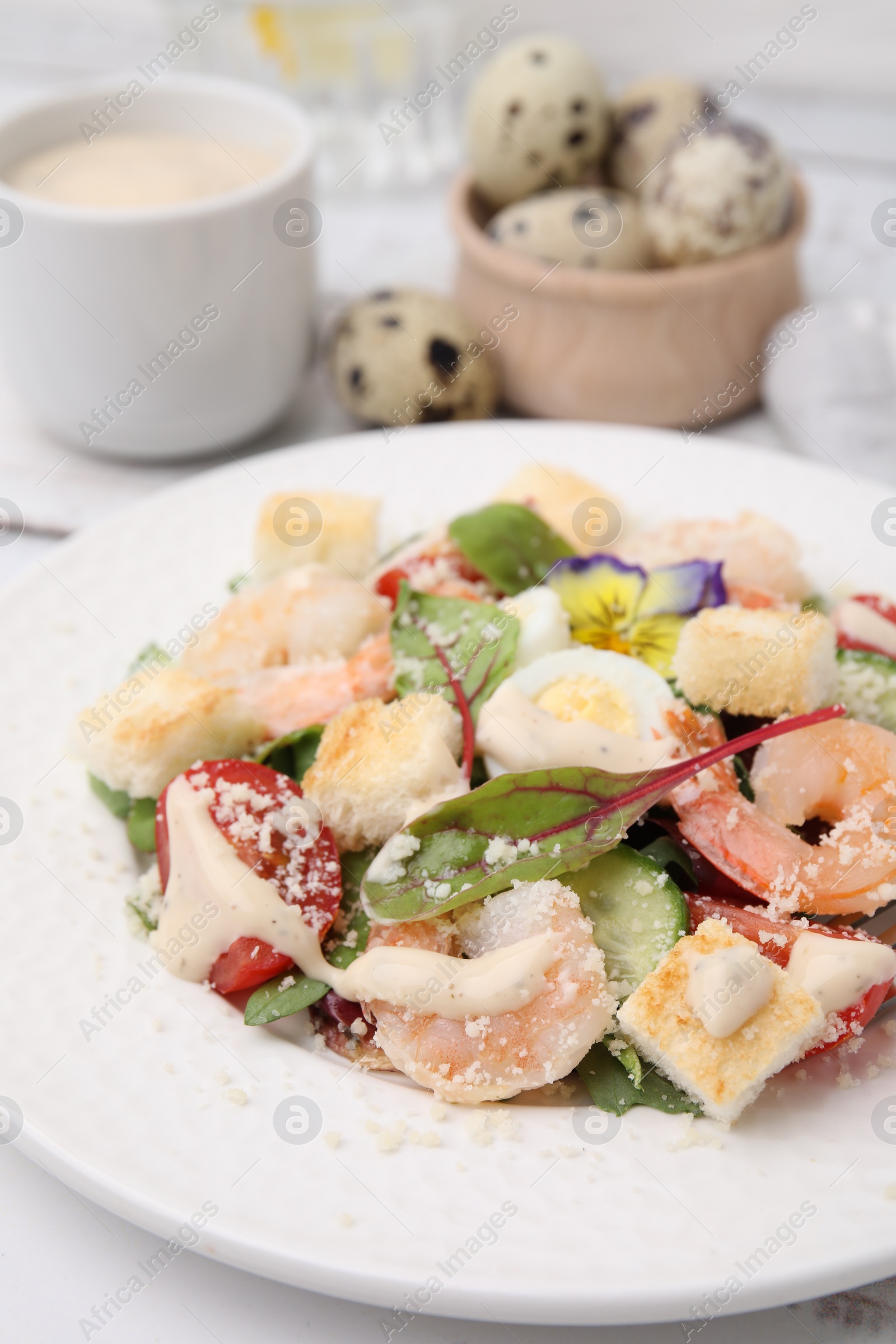 Photo of Delicious Caesar salad with shrimps on white table, closeup