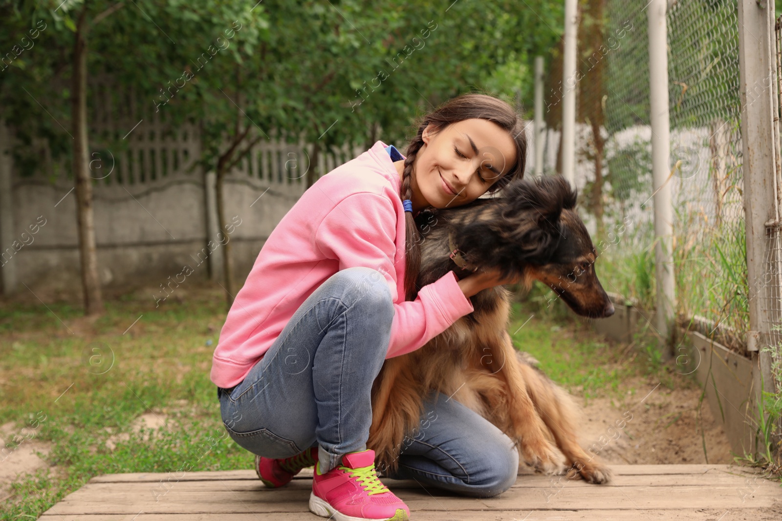 Photo of Female volunteer with homeless dog at animal shelter outdoors