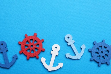 Photo of Anchor and ship wheel figures on light blue background, flat lay. Space for text