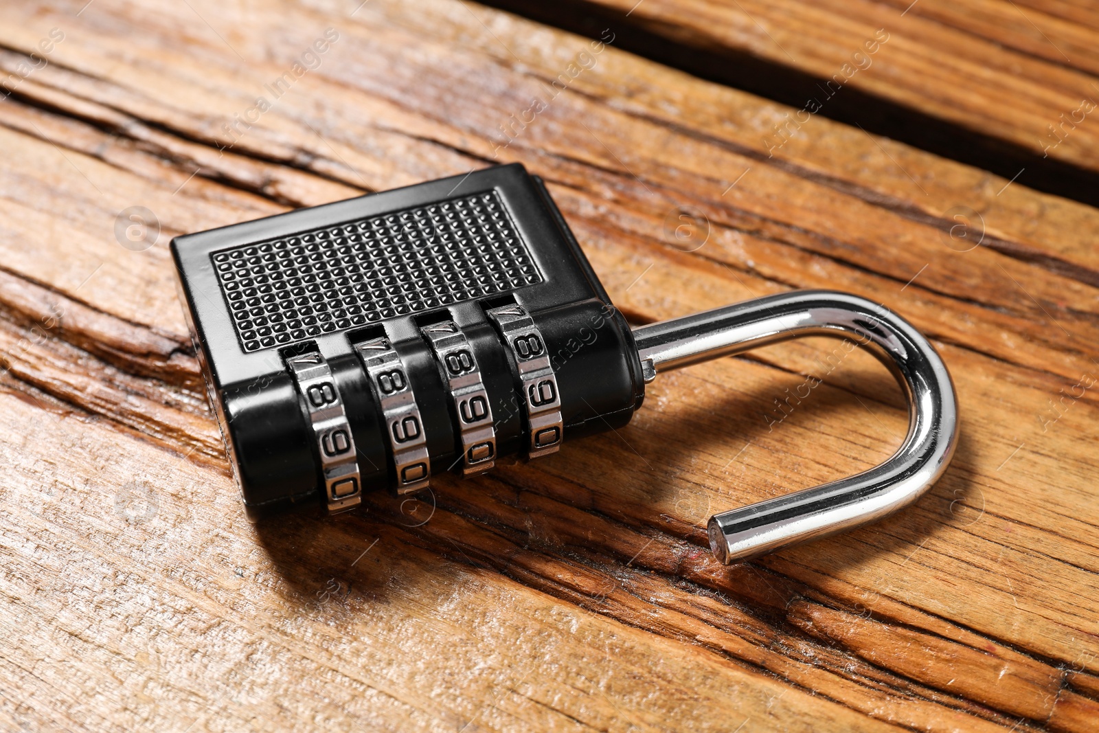 Photo of One steel combination padlock on wooden table, closeup