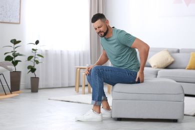 Photo of Man suffering from hemorrhoid in living room. Space for text