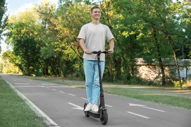 Photo of Happy man riding modern electric kick scooter in park