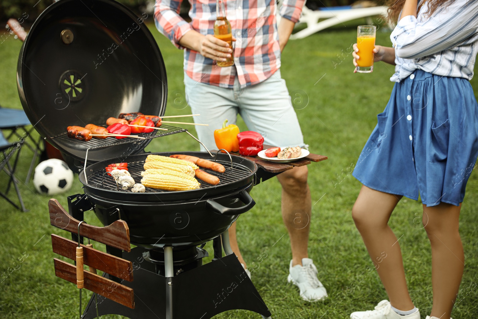 Photo of People with beverages near barbecue grill outdoors