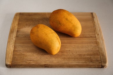 Photo of Delicious ripe yellow mangos on white table