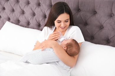 Photo of Woman feeding her baby from bottle on bed