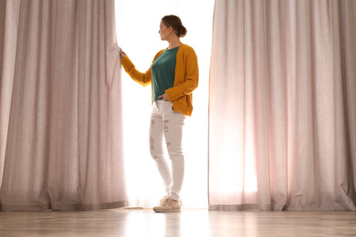 Photo of Woman near window with beautiful curtains at home in morning