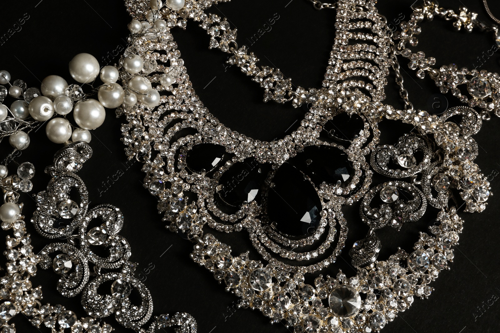 Photo of Different elegant jewelry on black background, top view
