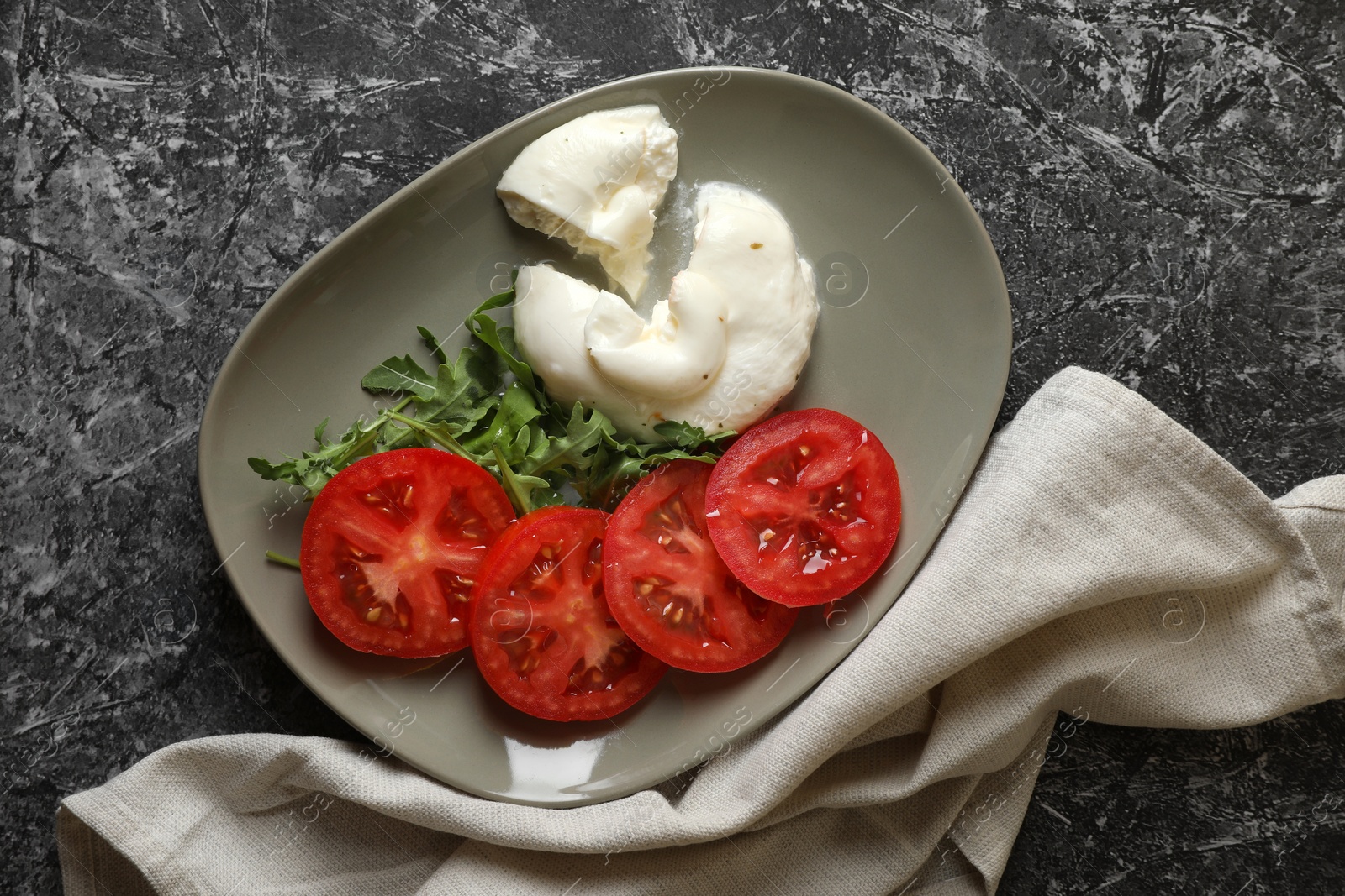 Photo of Delicious burrata cheese with tomatoes and arugula on grey table, flat lay