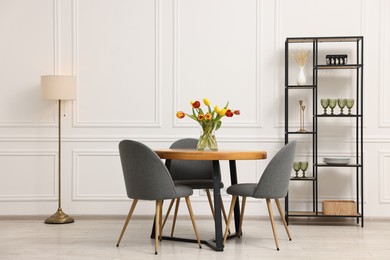 Photo of Stylish dining room interior with comfortable furniture and beautiful tulips