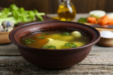Photo of Delicious chicken bouillon with parsley, carrot and eggs on wooden table, closeup