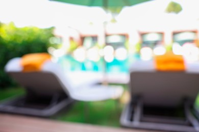 Photo of Sunbeds near swimming pool at luxury resort, blurred view