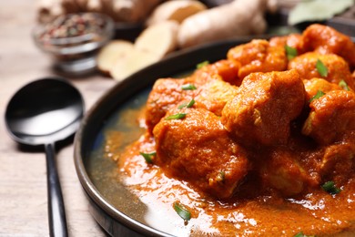 Plate of delicious chicken curry on wooden table, closeup