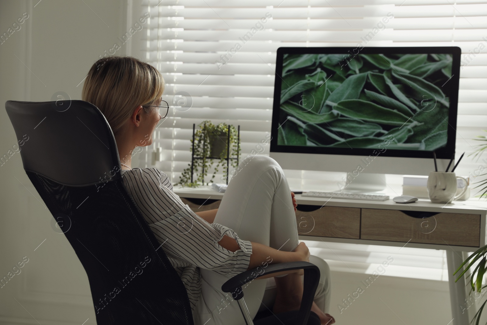 Photo of Woman resting on chair near workplace in room. Interior design