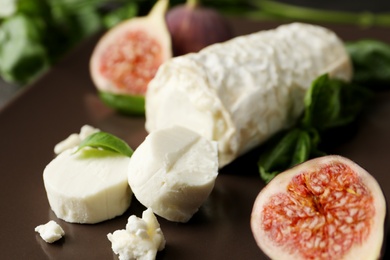 Photo of Delicious goat cheese with figs and basil on plate, closeup