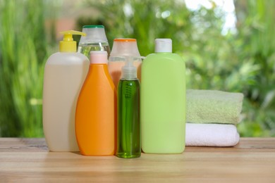 Photo of Different shower gel bottles and towels on wooden table