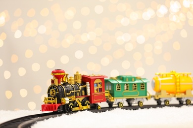 Photo of Toy train and railway on snow against Christmas lights