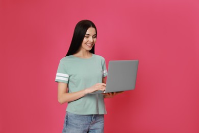 Photo of Young woman with modern laptop on pink background