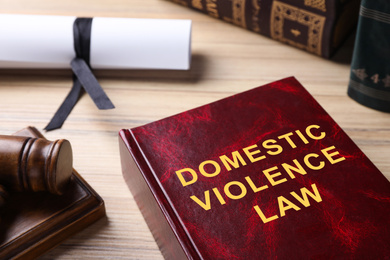 Image of Domestic violence law book on wooden table, closeup