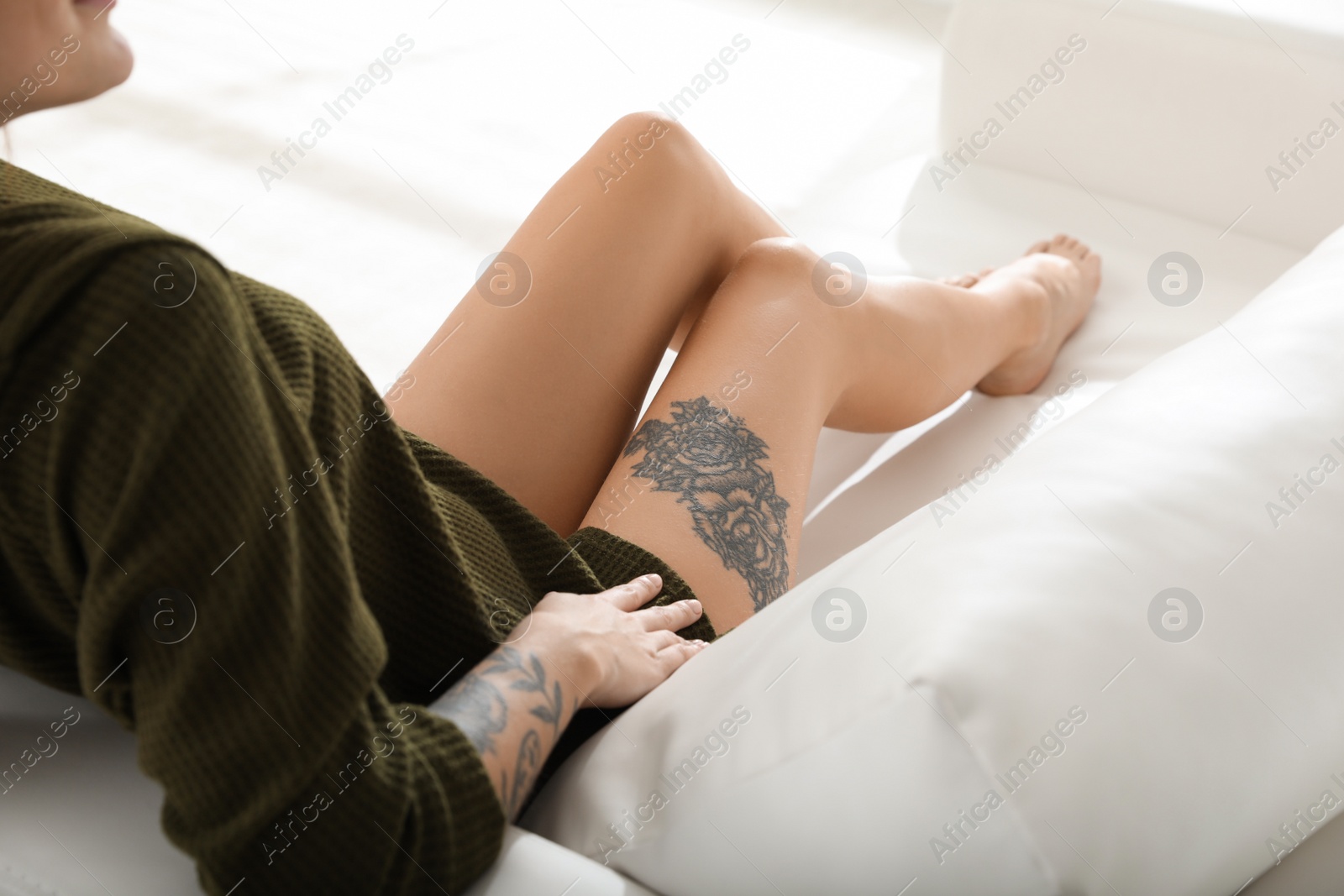 Photo of Beautiful woman with tattoos on body resting in living room, closeup