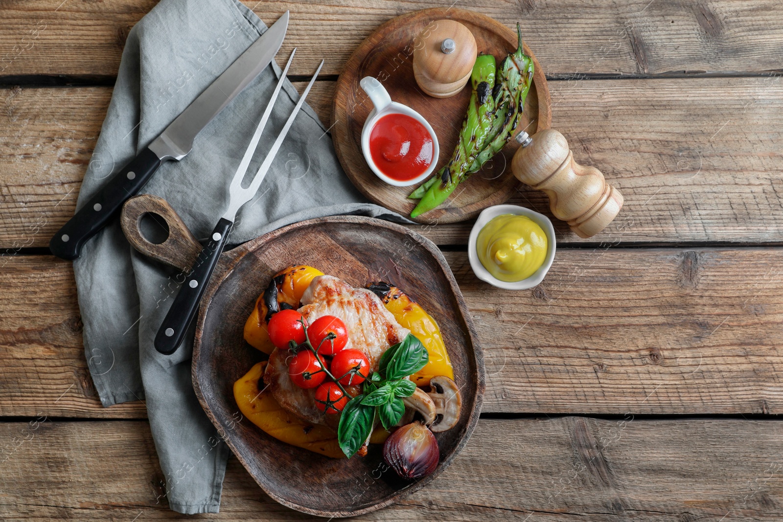 Photo of Delicious grilled meat and vegetables served with sauces on wooden table, flat lay. Space for text