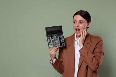 Photo of Emotional accountant with calculator on green background, space for text