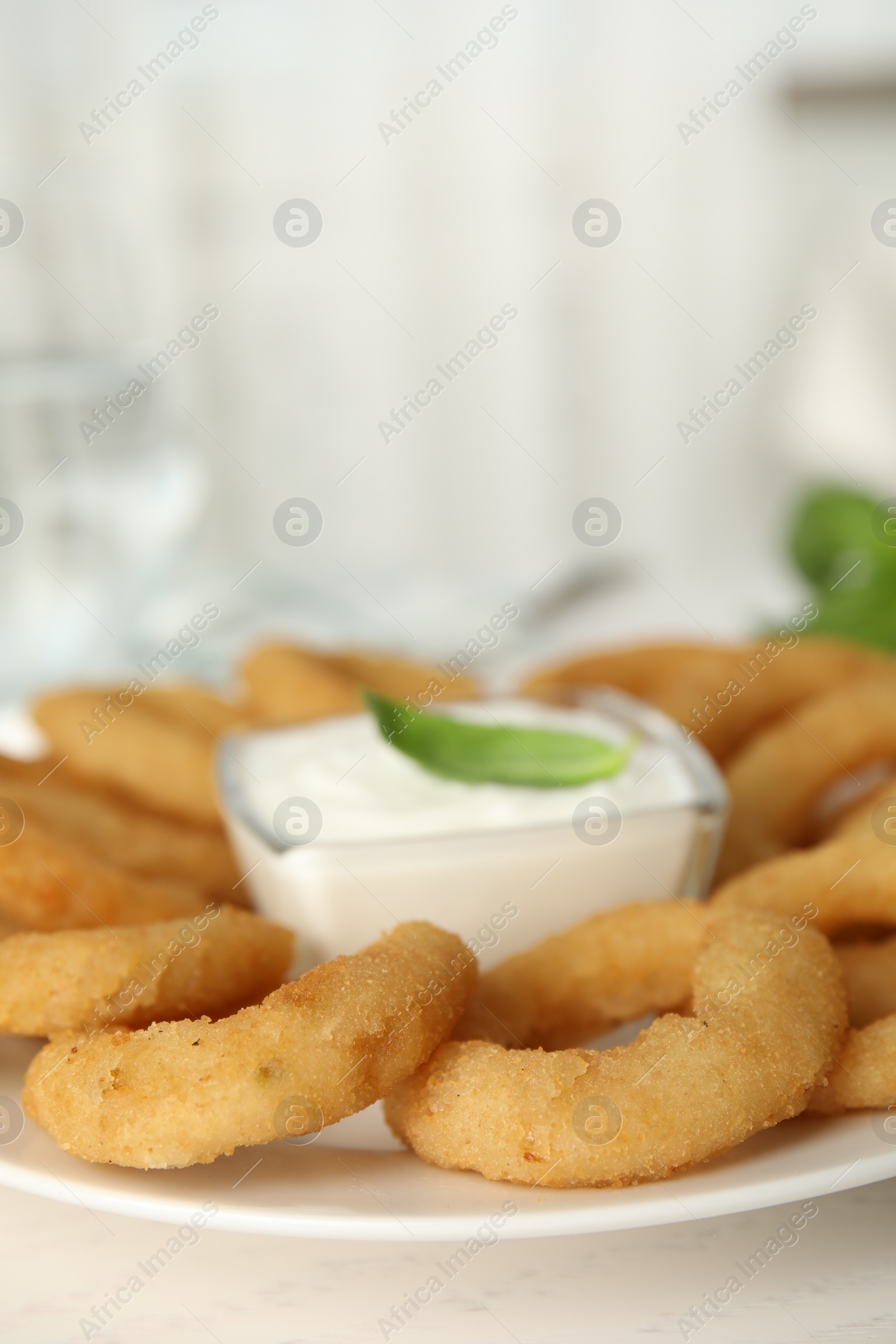 Photo of Delicious onion rings with sauce on white wooden table, closeup