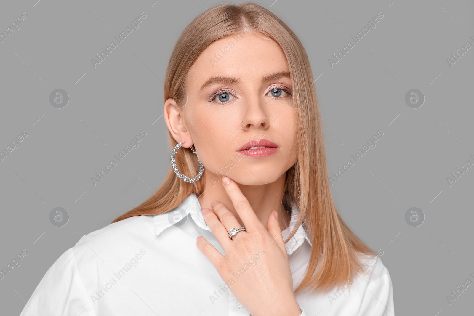 Photo of Beautiful young woman with elegant jewelry on gray background