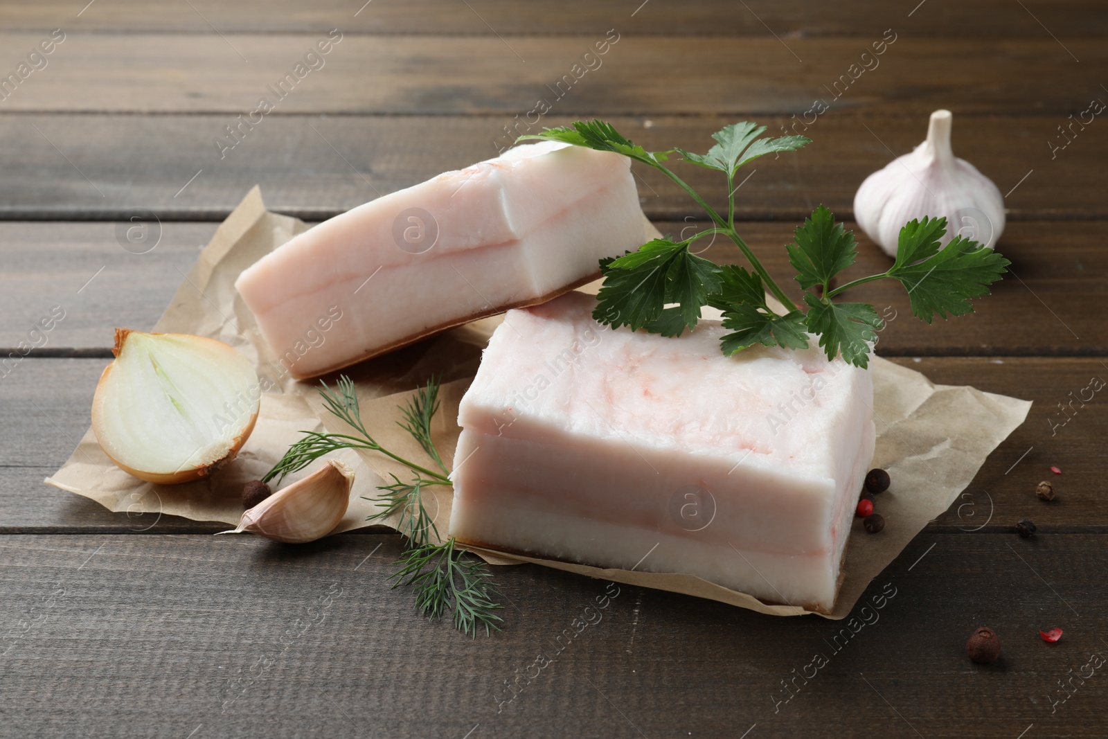 Photo of Tasty salt pork with herbs, onion and garlic on wooden table