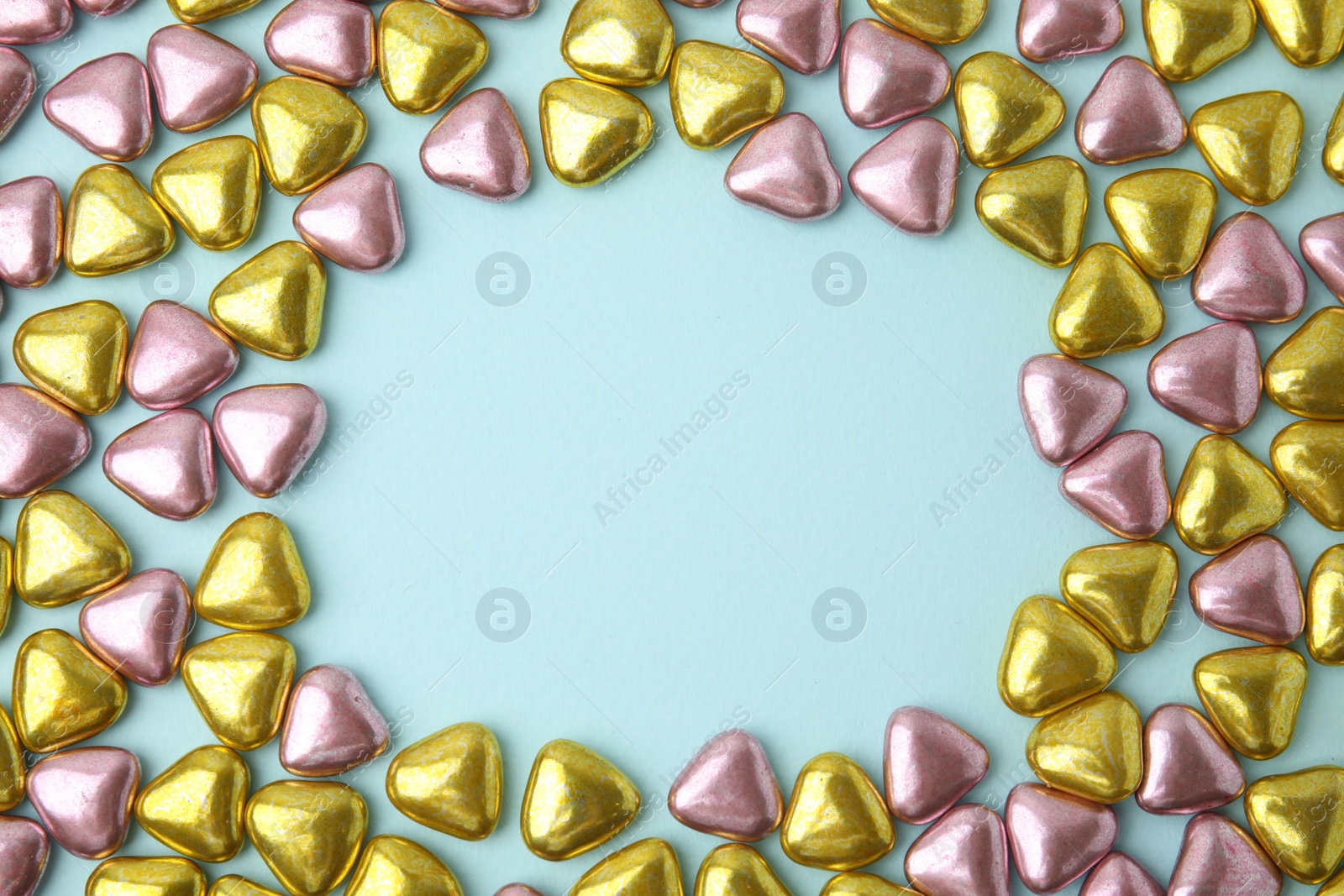 Photo of Frame made of delicious heart shaped candies on light blue background, flat lay. Space for text