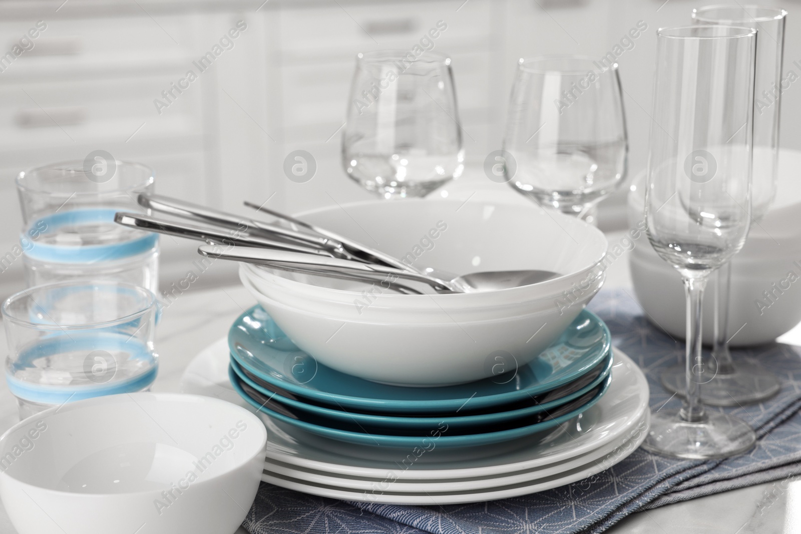 Photo of Different clean dishware, cutlery and glasses on white table in kitchen, closeup