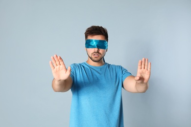 Photo of Young man with light blue blindfold on grey background