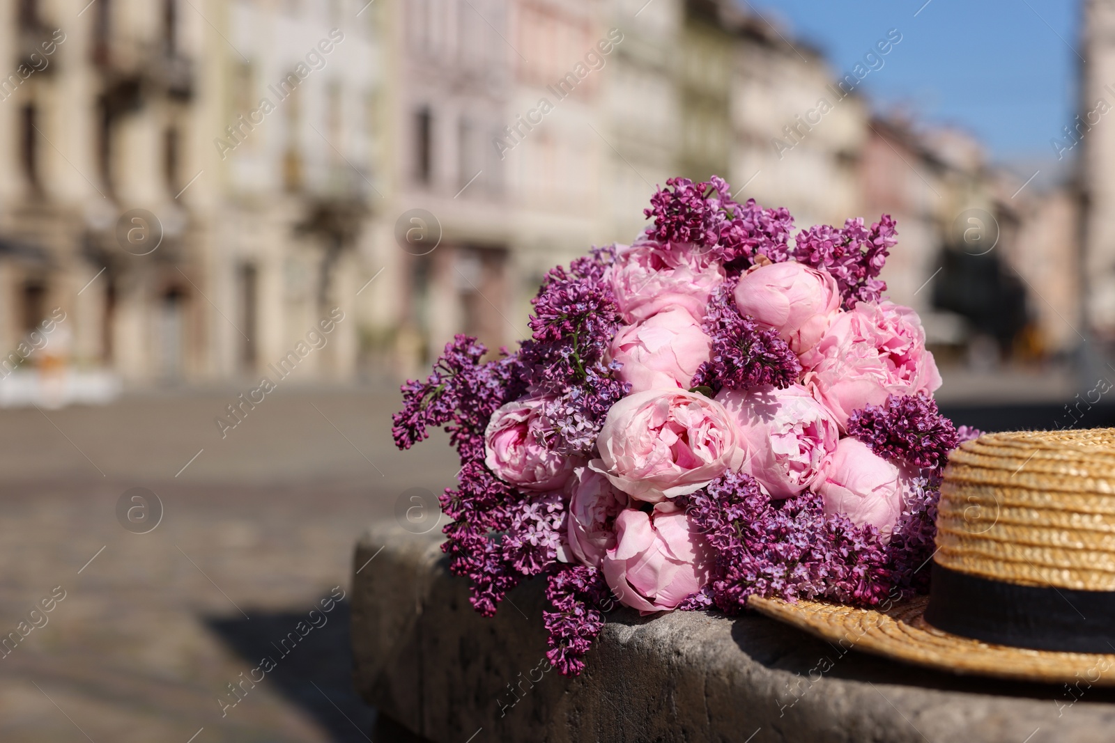 Photo of Bouquet of beautiful spring flowers and straw hat outdoors, space for text